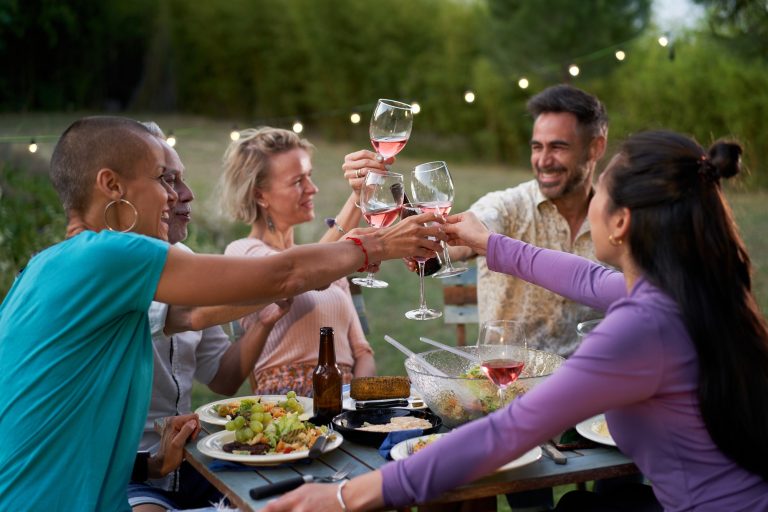 Happy friends having fun drinking red wine on backyard at private dinner party