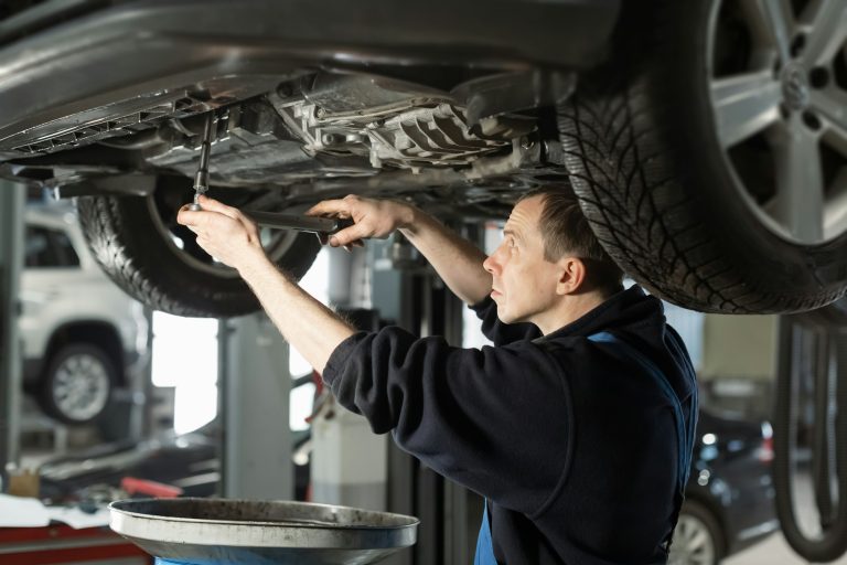 Mechanic in uniform is working in auto service