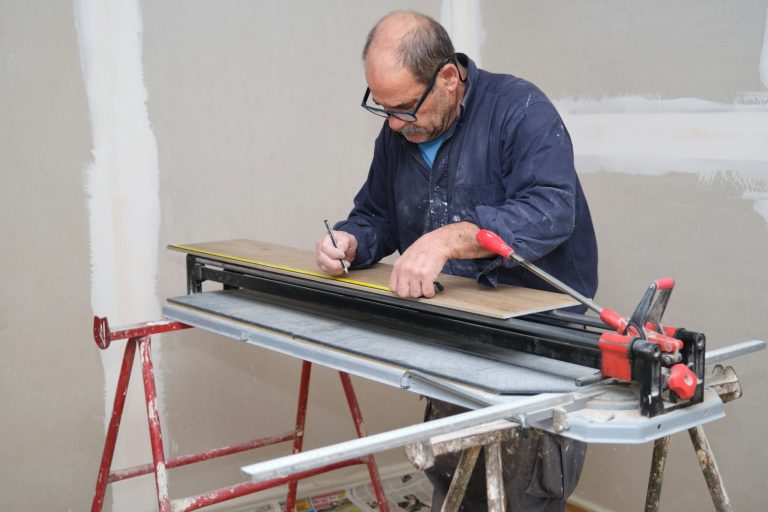 Senior contractor measuring a ceramic wood effect tile before cut it.