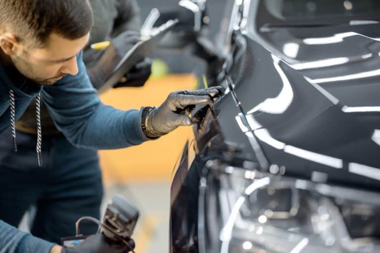 Worker examining vehicle body for scratches