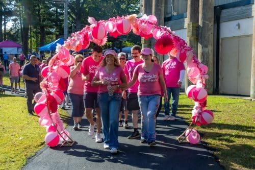Councilwoman Theresa Mari, Citizens Advocate Michelle Wright, Council, community officials and attendees walk under the Pink Arch - Pink in the Park 2025.