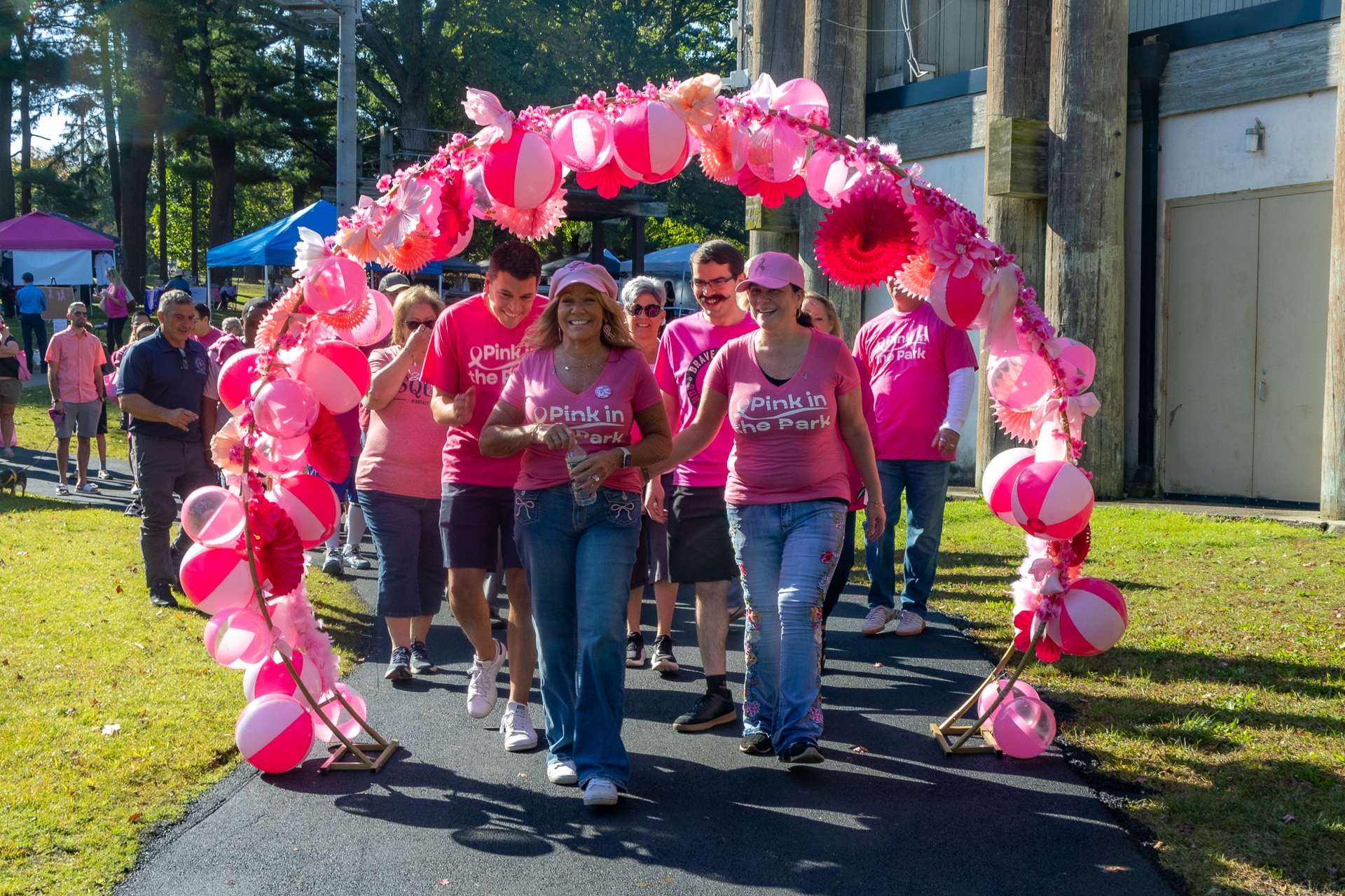 Councilwoman Theresa Mari, Citizens Advocate Michelle Wright, Council, community officials and attendees walk under the Pink Arch - Pink in the Park 2025.