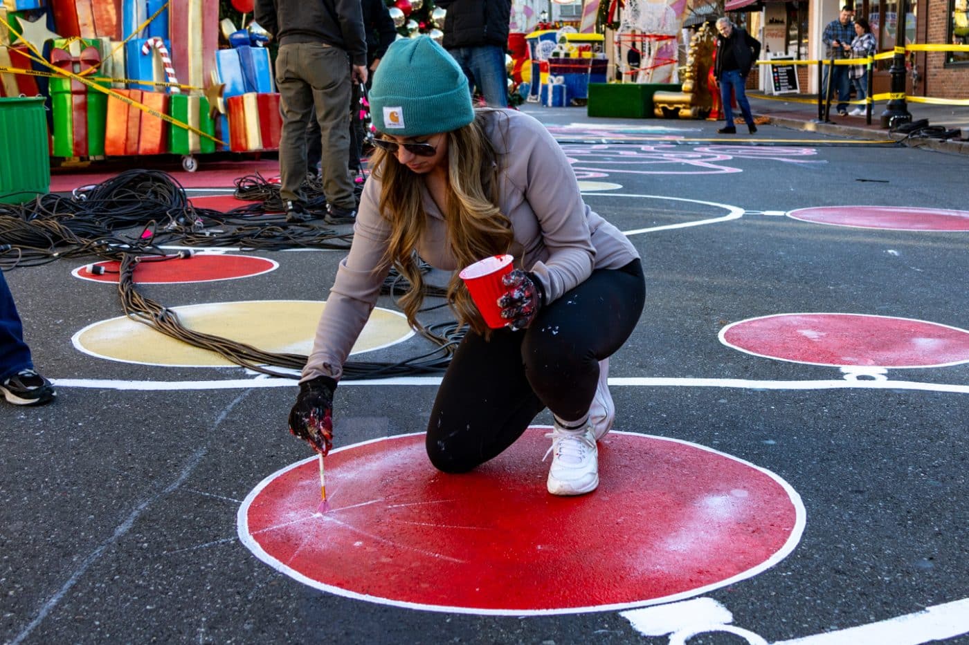 Artist Linday Lange adds sparkle to an ornament in the street mural. Holiday Spectacular Sneak Peek
