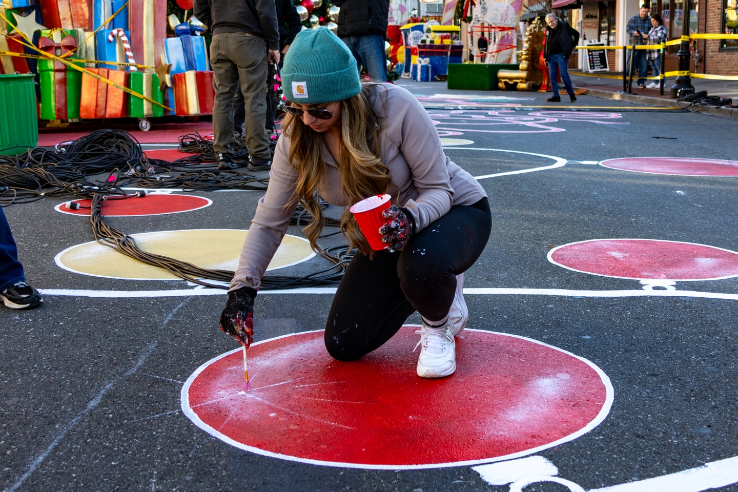 Artist Linday Lange adds sparkle to an ornament in the street mural. Holiday Spectacular Sneak Peek