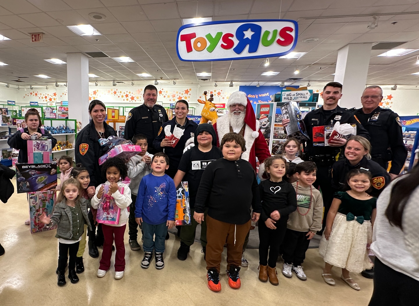 Santa Claus with Suffolk County Police Officers and Auxiliary Officers pose with 13 children of all ages. Macy's Shop With A Cop
