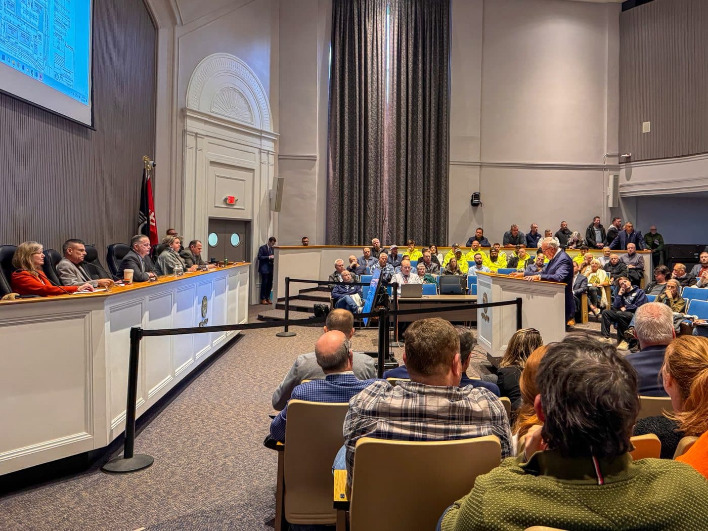 Town Board, Speaker with full auditorium side view. Melville Crossing Public Hearing Draws Strong Reactions