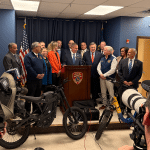 Suffolk County Police Commissioner Kevin Catalina with Town of Huntington Legislators Stephanie Bontempi (orange) and Rebecca Sanin (bright blue) together with officials with illegal e-bikes. Suffolk County Enforces New E-Bike and E-Scooter Laws Focused on Safety