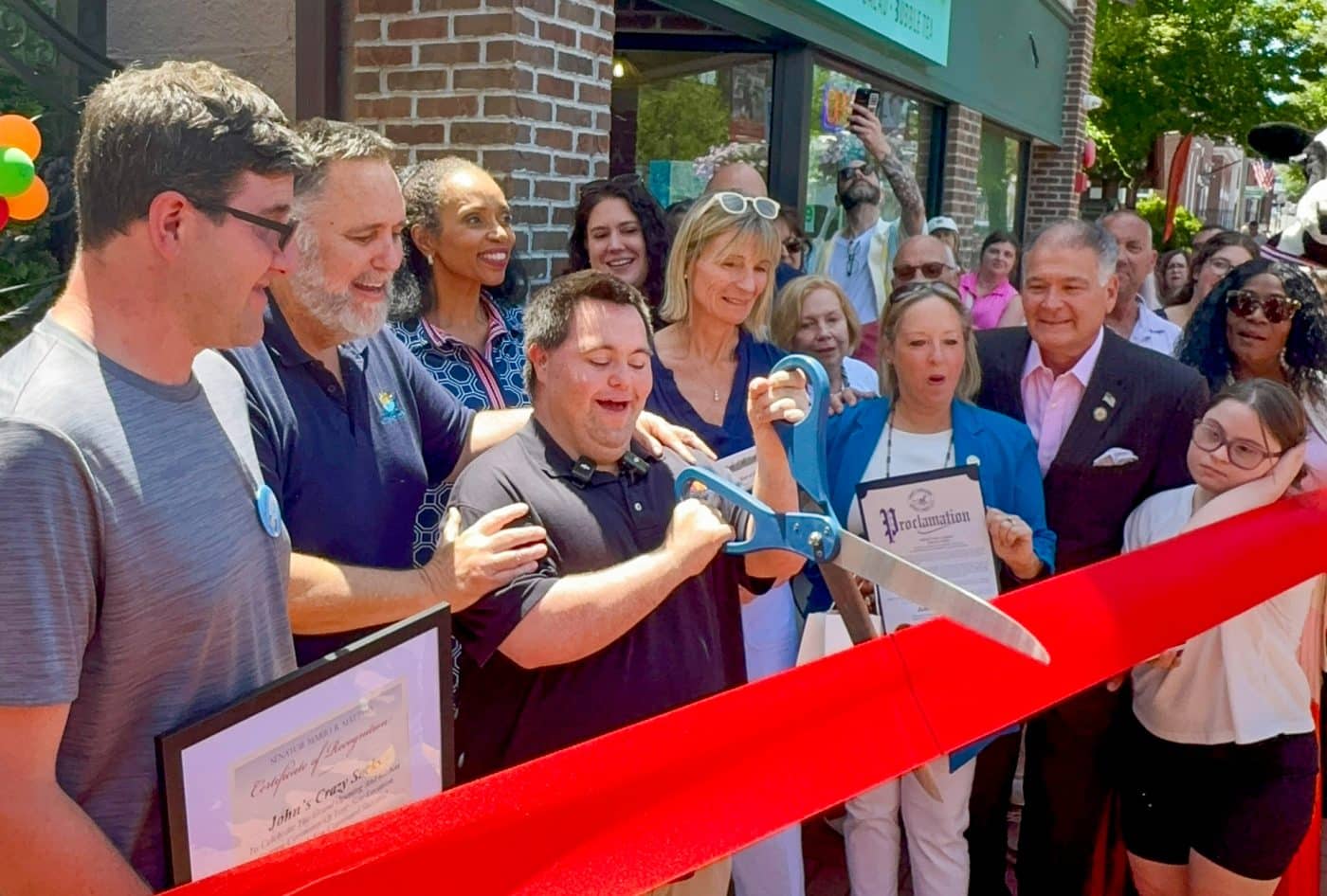 John Cronin cuts the ribbon with his father and Co-Founder Mark Cronin on their new Retail Store at 328A Main St, Huntington, NY. To their right: Town of Huntington's Receiver of Taxes Jillian Guthman; Jennifer Cassidy - Chair, Huntington Township Chamber of Commerce; Suffolk County Legislator Stephanie Bontempi (white glasses); Suffolk County Legislator Rebecca Sanin; New York State Senator Mario Mattera; and Huntington Township Chamber of Commerce Board Member and Chez Laa Reine Boutique Owner Rhonda Taylor-Gooden. John's Crazy Socks Opens First Retail Store in Huntington Village