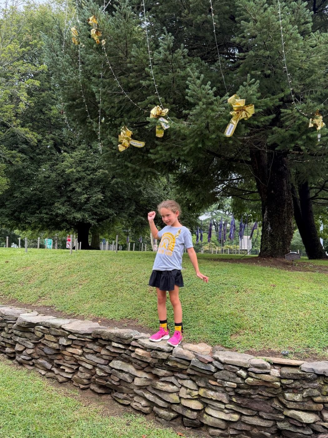 Cancer Survivor Ariella Kalmar shows her strength with a flex pose. Huntington Goes Gold: Tree Lighting Shines a Light on Childhood Cancer