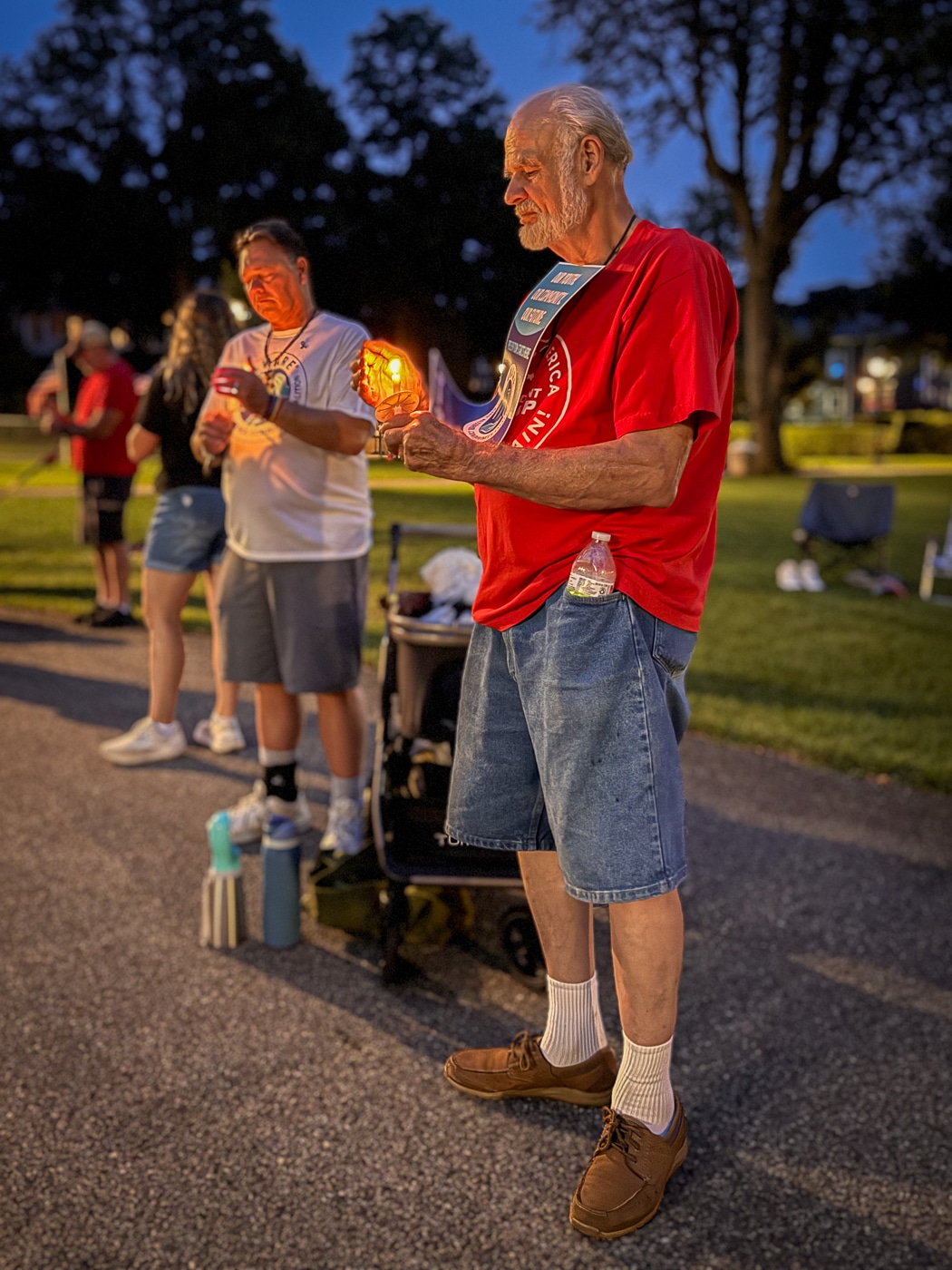 Two men shelter their candle's flame from the wind. Photo Stories: Every Light Honors a Life