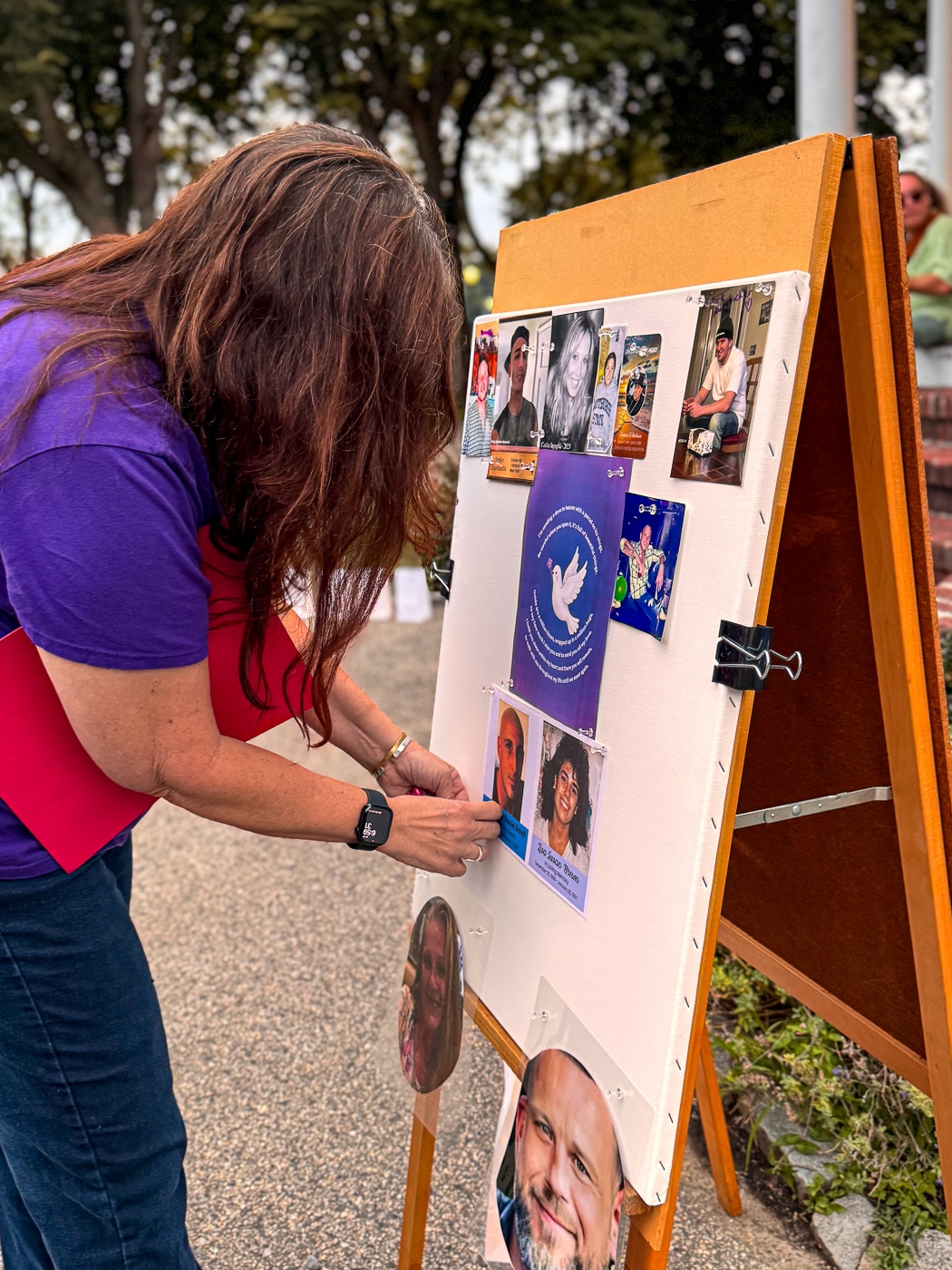 June Margolin - Huntington Matters pins photos of Diane Schaber's son Chris Revell and June's sister Lisa Brown to the memorial board. Photo Stories: Every Light Honors a Life