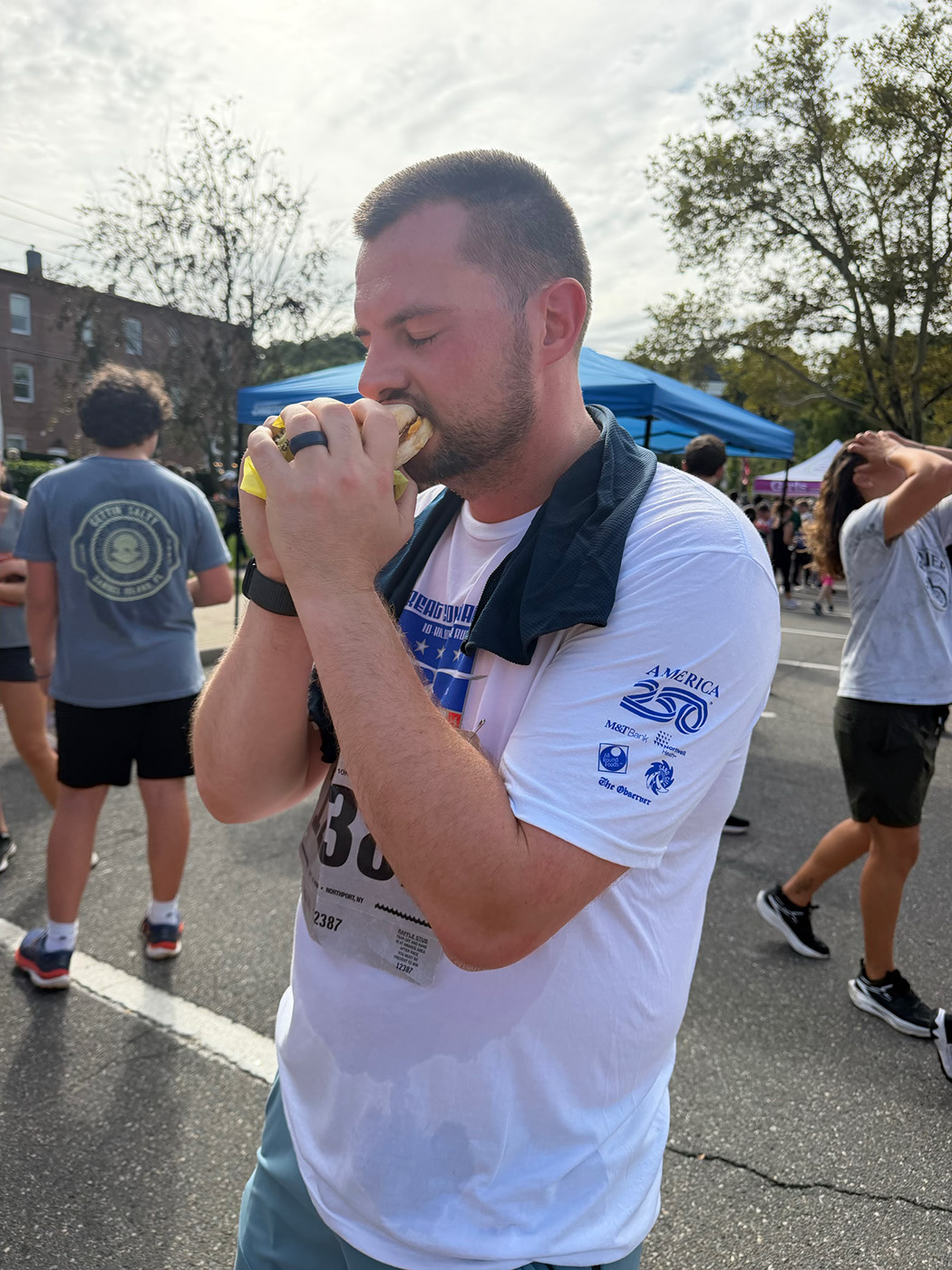 Tyler Cobe Eating His Egg McMuffin At The Finish. The Great Cow Harbor 10K Run 2026 in Northport NY